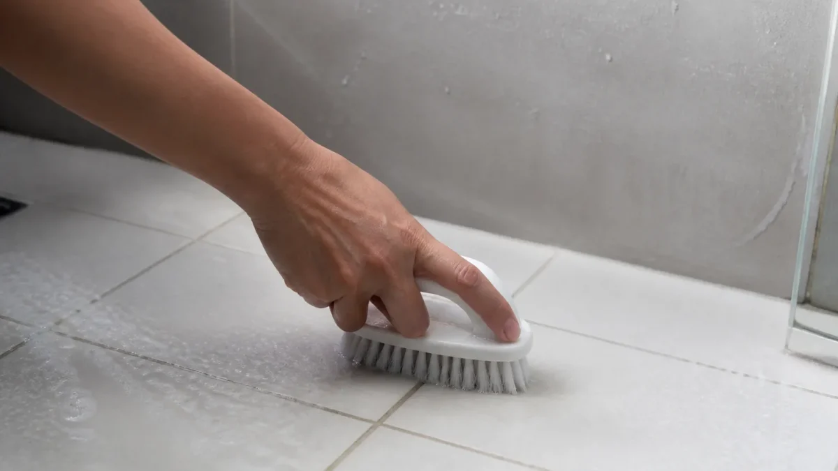 Main tenant brosse blanche nettoyant carrelage salle bain