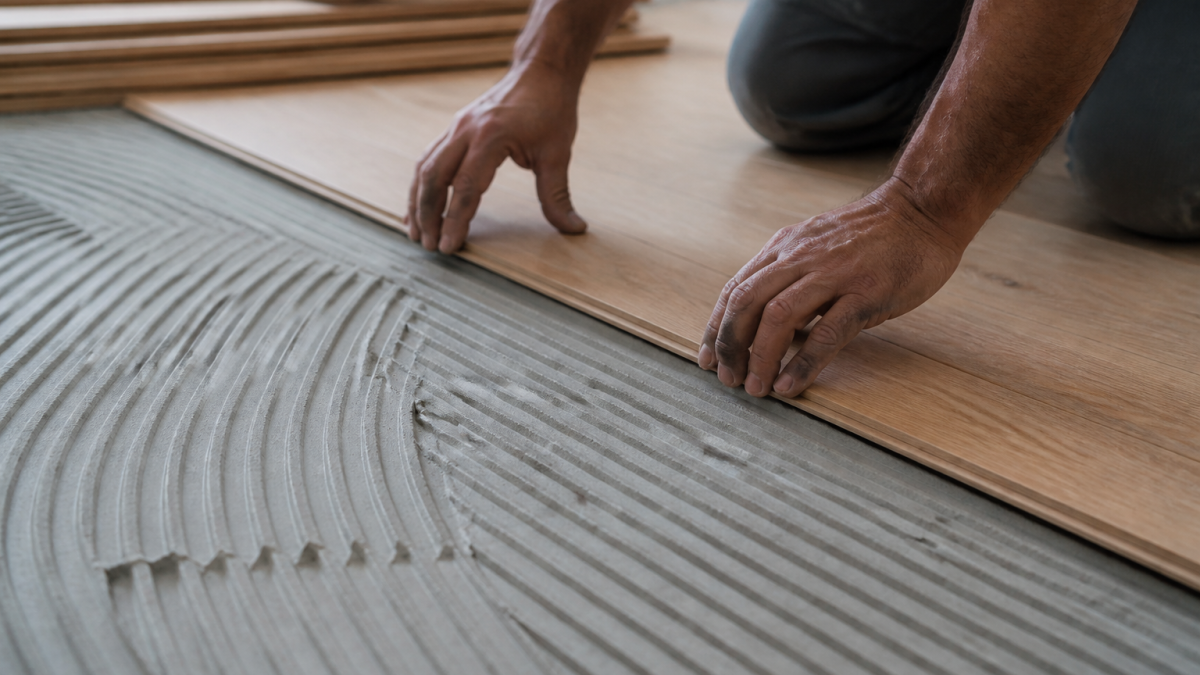 Mains posant lames de bois sur sous-couche grise