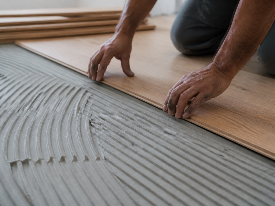 Mains posant lames de bois sur sous-couche grise