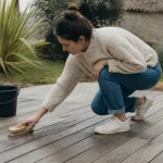 Personne accroupie recourant terrasse bois avec brosse